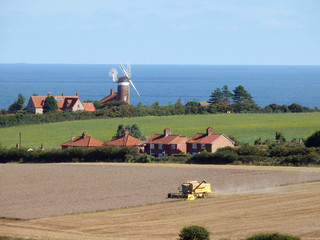 Combine harvester  with windmill and Norfolk Coast i
