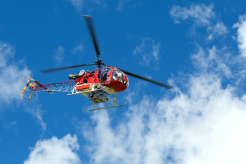 Fototapeta na wymiar Red helicopter on the blue sky