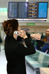 Asian businesswoman on her cellphone while looking at her watch,