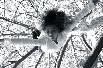 a girl swinging upside down from a tree 
