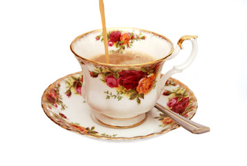 English tea being poured into tea cup on white background
