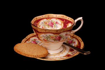 Empty cup and saucer with biscuit on black background