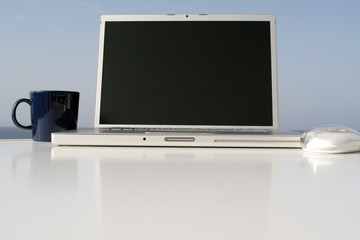Laptop, Notebook mit Maus und Tasse auf Tisch draussen