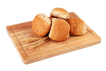 Fresh bread rolls on rustic chopping board 