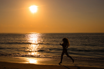 Female running along the beach at sunrise