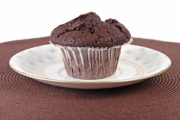Chocolate chip muffin in paper case on brown place mat