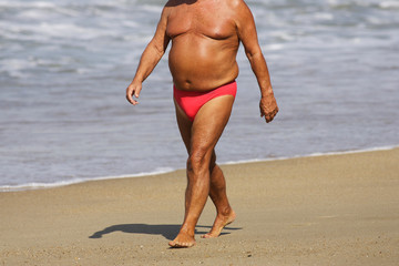homme avec embonpoint qui marche sur la plage