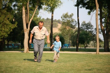 Fototapeta premium Grandfather with grandson runing on the park