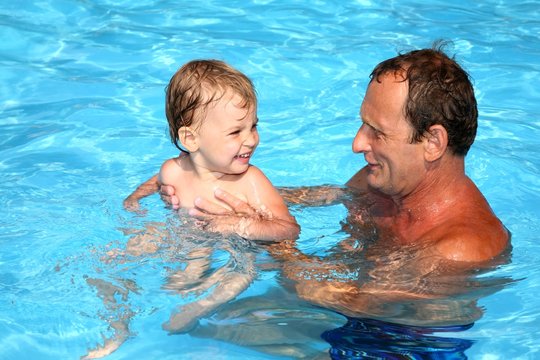 Grandfather with granddaughter in the pool 