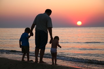 Grandfather with grandchildren on sunset at sea 