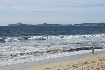 A small boy runs excitedly down to the waves