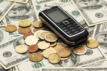 Mobile phone with coins  and dollar bank notes