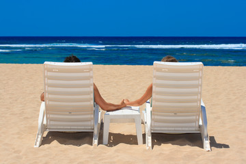 Couple in beach chairs holding hands