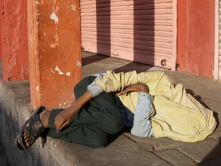 Homeless person sleeping near the road with flys