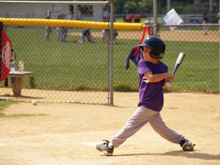 young baseball player after swinging watching ball