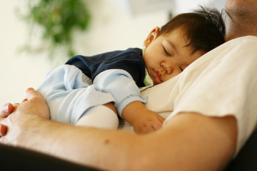 Adorable and sweet little baby sleeping on Dad's chest