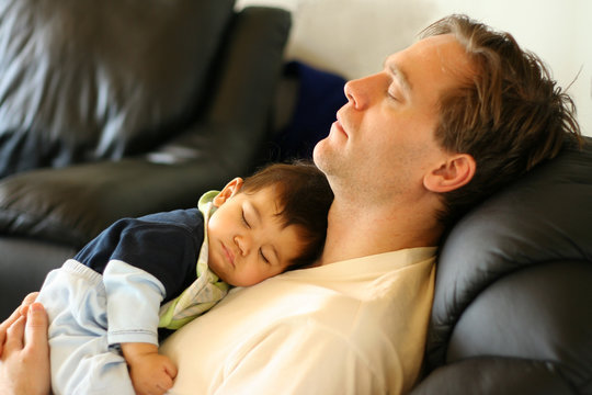 Father Sleeping On Chair With His Baby Boy On Chest