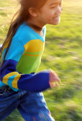 Obraz premium Young girl running on a grassy field, speed blur with sun flare