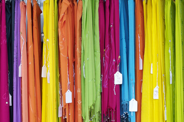 Brightly colored spring dresses on an outdoor sales rack
