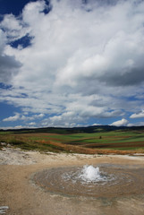 geyser in the landscape with clouds in the background