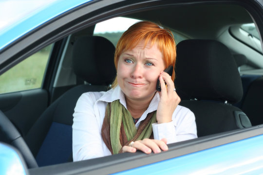 Red-haired woman with mobile-phone in a car. 