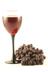Grapes and a glass with red wine isolated on white.