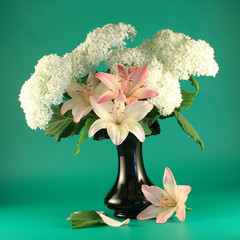 Flowers of a pink lily and  white hydrangea  in a vase.