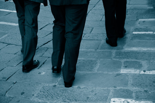 Three Business Men Walking Together Down The Street