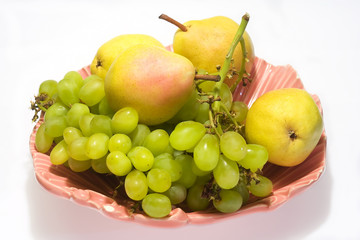pears and grapes in pink vase with white background