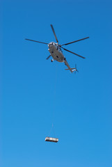 Fly big white helicopter with cargo on rope
