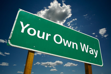 "Your Own Way" Road Sign with dramatic blue sky and clouds.