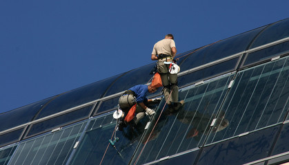 Roped craftsmen work on the glass roof of a hotel