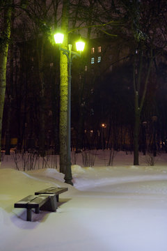 Bench In A Snowy Park At Night