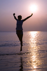 Girl jumping under water in sunset  