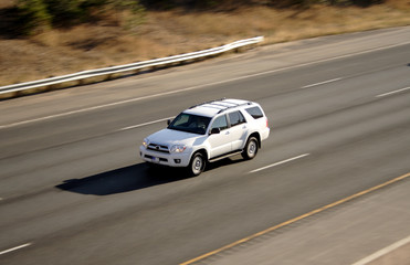 Fototapeta na wymiar Pan Blur of White Vehicle on Highway