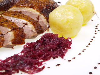 geröstete gänsebrust mit kartoffelknödel und rotkohl freigestellt auf weißem hintergrund