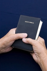 Old hands holding worn Bible