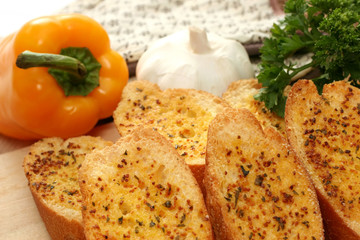 Toasted garlic bread on a wooden tray with yellow capsicum