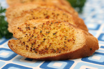 Garlic bread slices laid on a retro blue squared table-mat