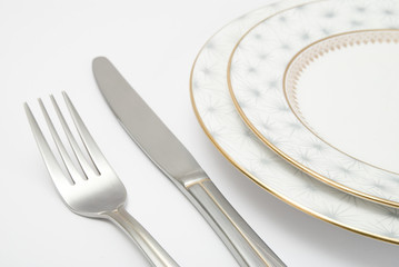 Table setting with plates knife and fork on white background