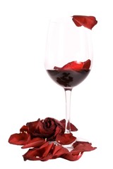 Glass on red wine with a rose and rose petals isolated on white