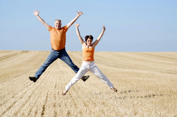 couple sautant dans un champ de blè