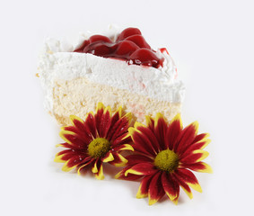 Piece of white cream cake and flowers isolated on white.