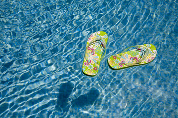 green flip flops floating in the swimming pool