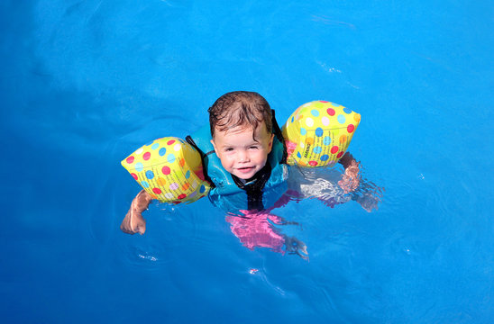 Girl toddler floating on top of swimming pool