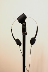 Small black headphones on black microphone stand