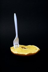 White plastic fork stuck in a buttered bagel