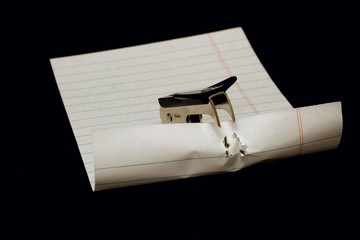 Staple remover biting piece of white lined paper