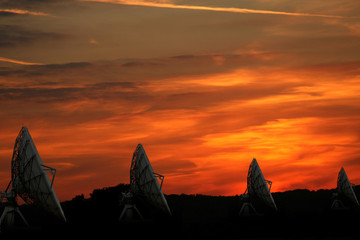 row of large satellite dishes as the sun sets - obrazy, fototapety, plakaty