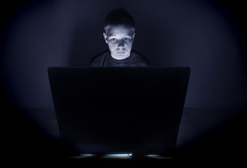 Boy illuminated by the blue light of a computer monitor